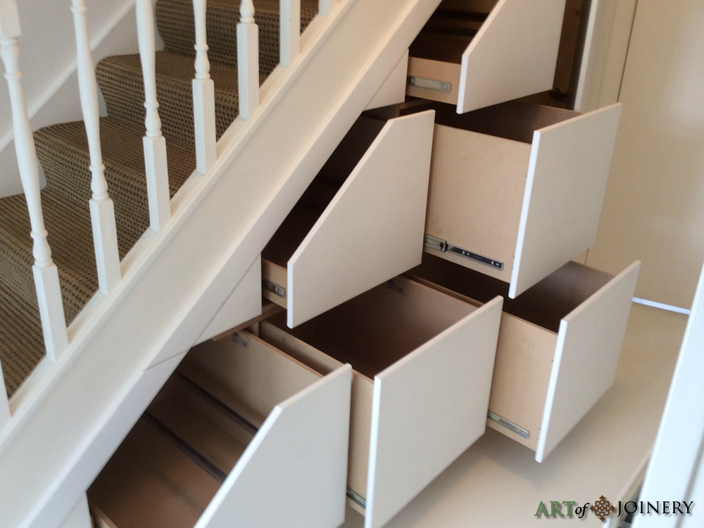 Open pull-out drawers fitted beneath a staircase
